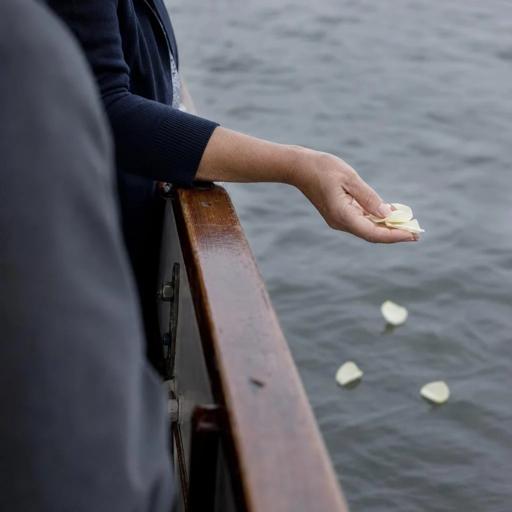 Illustration of a quiet farewell, with flower petals held over the side of a boat