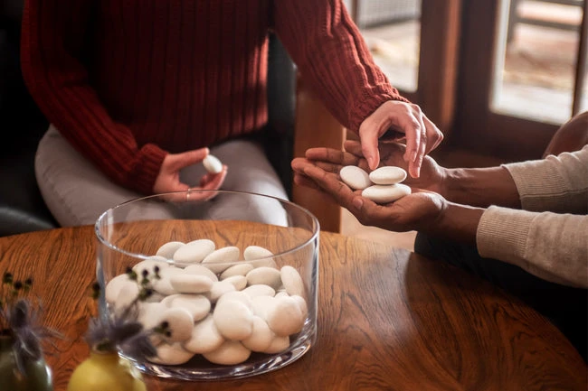 Two people sharing memories across a table, handling smooth stones